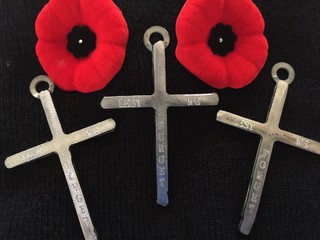two poppy pins and three metal crosses