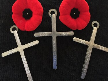 two poppy pins and three metal crosses